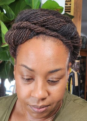 Woman with intricately twisted and styled hair looking down.