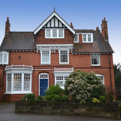 Large brick house with a blue front door and bay windows.