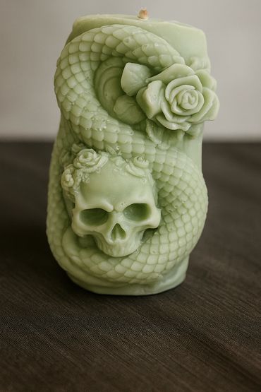 Green skull-shaped candle with a detailed snake wrap design.