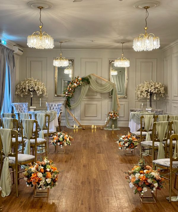 Elegant indoor wedding setup with floral decorations and chandeliers.