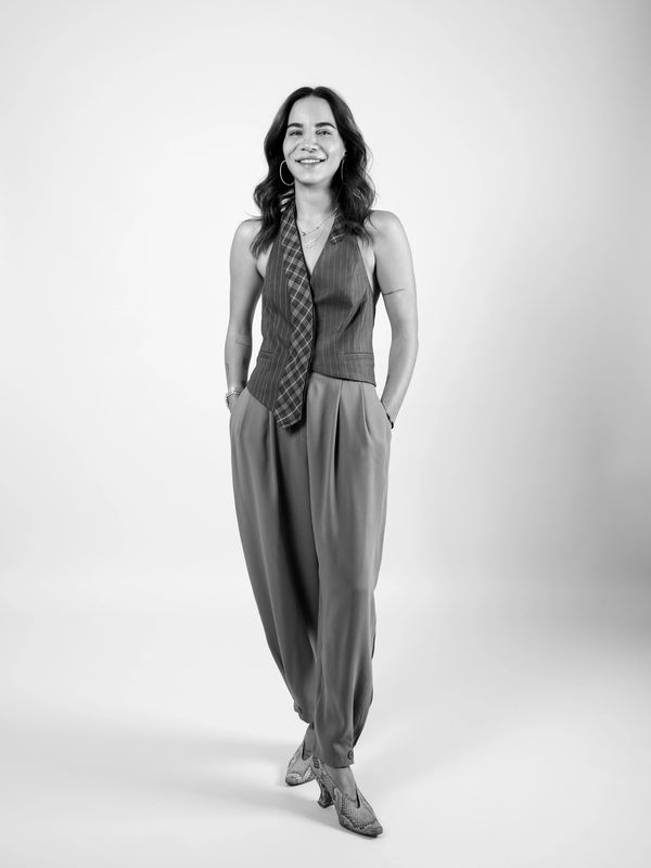 Smiling woman in stylish pants and sleeveless top posing confidently.