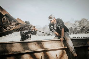 Two men working with heavy machinery and chains outdoors.