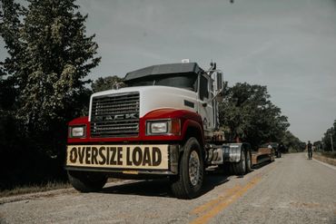 A large Mack truck with an "Oversize Load" sign parked on a rural road.