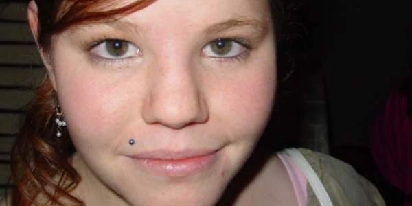 Close-up of a young woman with a lip piercing and light makeup.