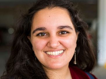 Smiling woman with long dark hair and dangling earrings.