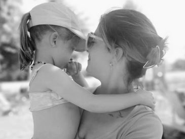 A mother lovingly holds her daughter close at the beach.