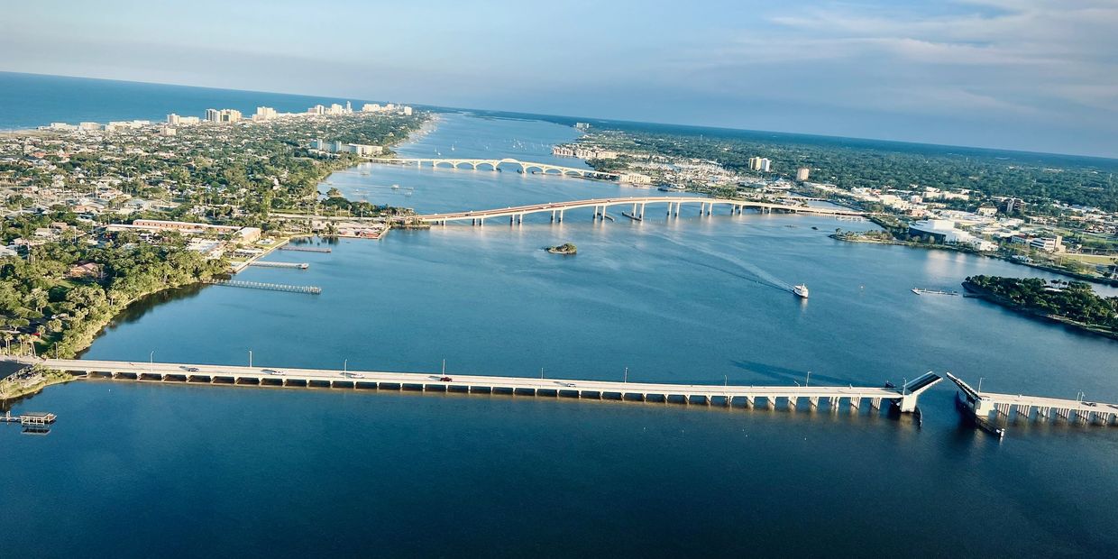 Aerial view of a city with multiple bridges over a large river leading to the ocean.
