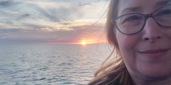 Woman smiling with ocean sunset in background.