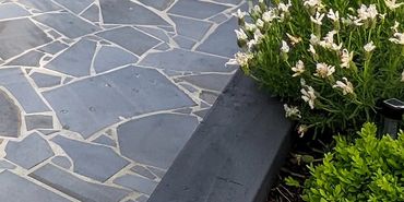 Cozy outdoor patio with a white pergola, cushioned seating, and lush garden surroundings.