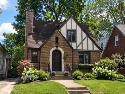 Charming brick Tudor-style house with a manicured front lawn and flower beds.