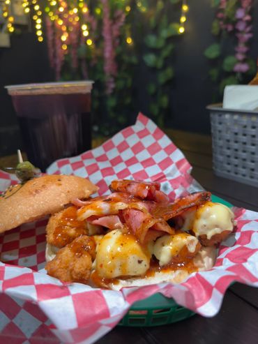 Loaded sandwich with fried chicken, bacon, and melted cheese.
