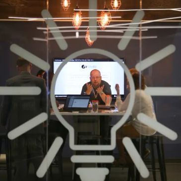 People engaged in a meeting behind a glass wall with a lightbulb design.