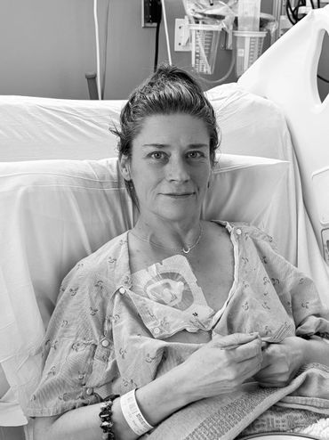 Woman in hospital bed with medical devices and wristband.