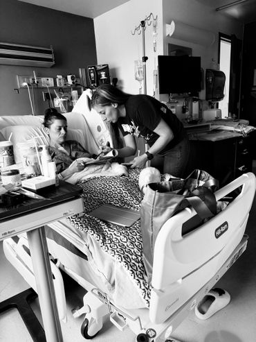 A woman assists a patient in a hospital bed with reading material.
