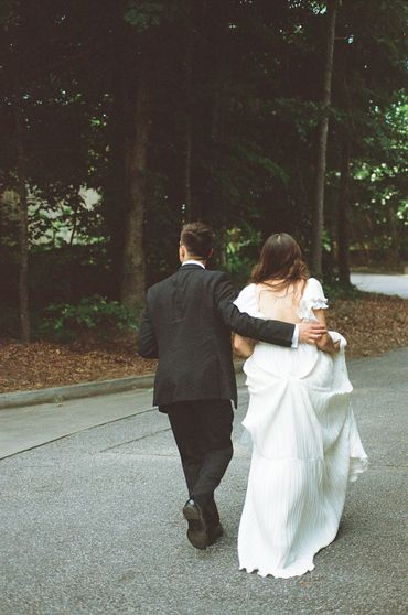 Couple walking arm in arm on a quiet forest road, dressed formally.