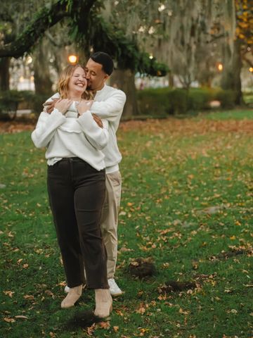 Couple enjoying a warm embrace in a park during autumn.