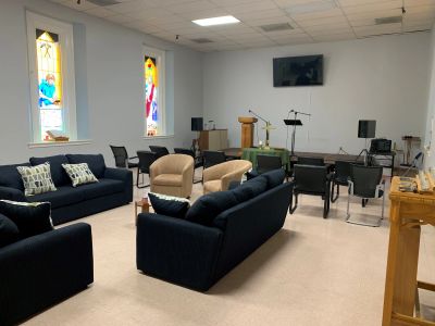 Comfortable seating area in a small chapel with stained glass windows.