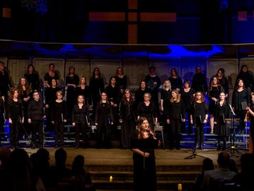 Choir performing on stage under blue lighting.