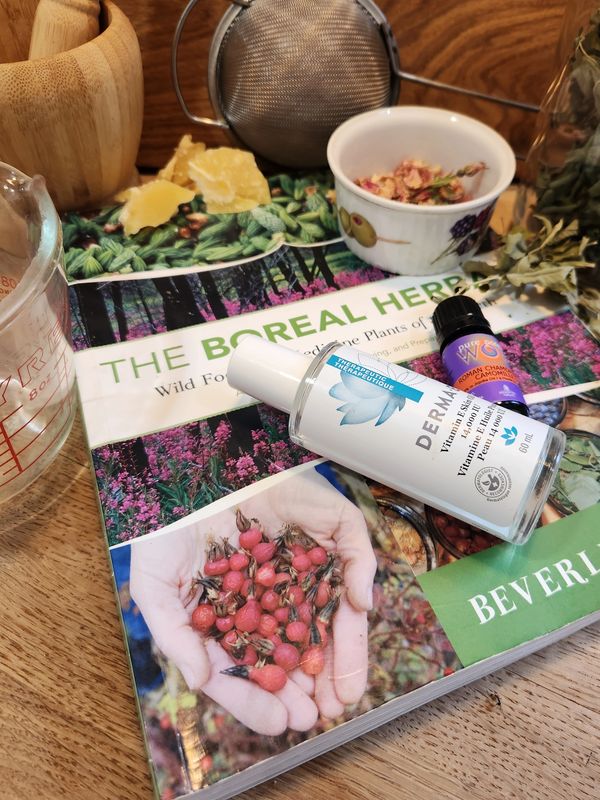 Skincare products and herbal book on wooden table with tea accessories.