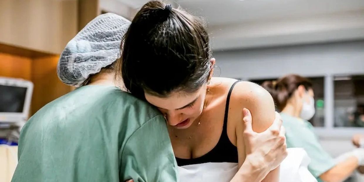 A woman embraces a person in medical scrubs, showing emotional support.