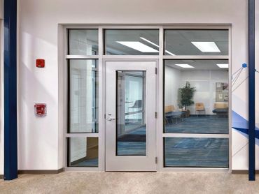 Modern glass door leading to a room with chairs and plants.