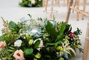 Botanical style aisle flowers and centrepiece with candle detail.