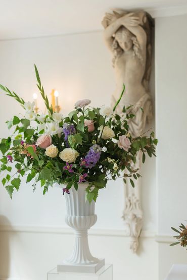 Close up of wild, untamed and romantic floral design in an urn at plas maenan ceremony in pastels