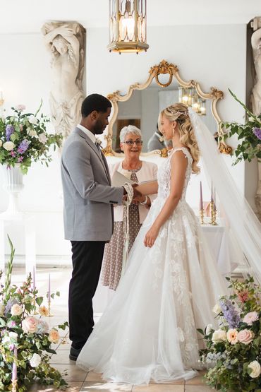 Bride and Groom at ceremony saying vows with registrar surrounded by pastel flowers