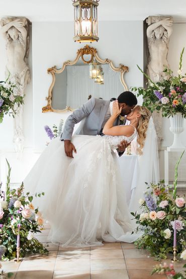Couple posing in ceremony space surrounded by flowers and candles, light and airy wedding