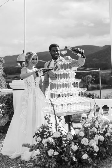 Couple pouring champagne onto champagn tower with tall floral meadow at the base for a luxury look