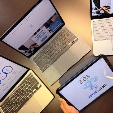 Four devices including laptops and a tablet displaying tech-related content on a table.