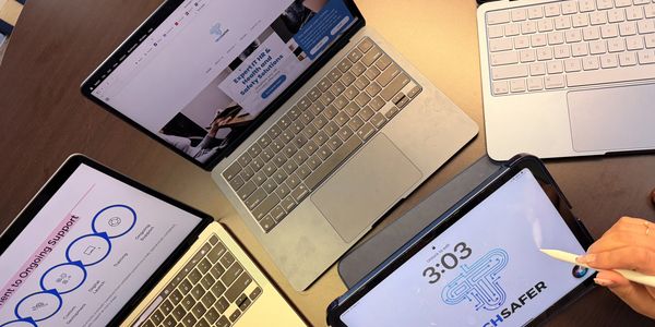 Four laptops and tablets on a desk, one with a stylus in use.