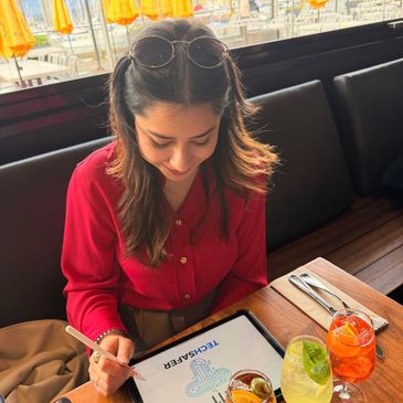 Woman in red blouse looking at a menu in a restaurant with colorful drinks.