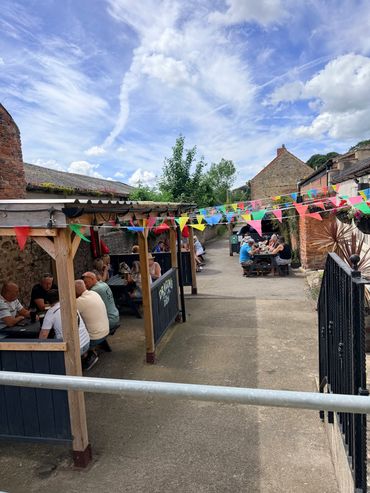 People enjoying drinks and conversation in a colorful outdoor pub setting.