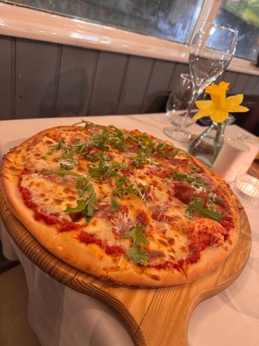 Freshly baked pizza topped with cheese, tomato sauce, and arugula.