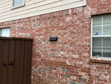 Brick house exterior with a brown gate and windows.