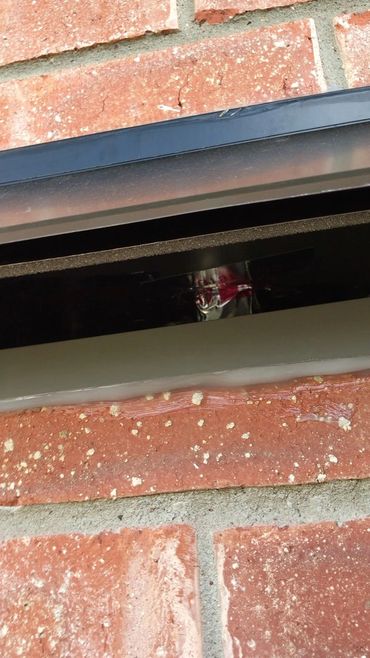 A close-up of a black mailbox slot on a red brick wall.