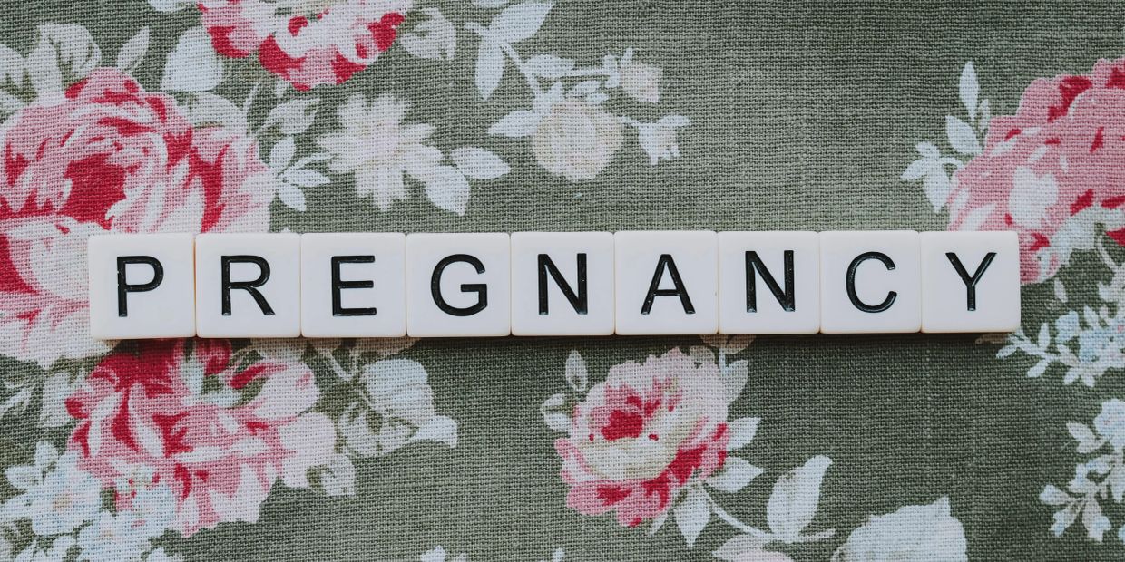 The word 'PREGNANCY' spelled out on floral fabric.