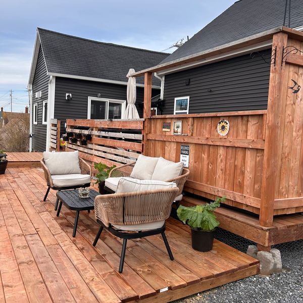 Cozy outdoor seating area on a wooden deck with cushioned chairs and a small table.