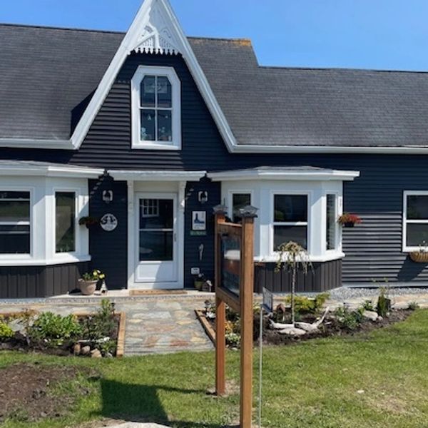 Charming black and white cottage with a well-kept garden and clear blue sky.