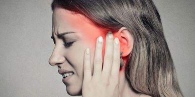 A patient experiencing earache or barohypoacusis, symptoms commonly associated with TMJ disorders.