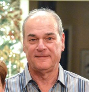 Smiling elderly man in striped shirt.