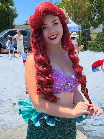 Woman dressed as a mermaid with red hair smiles.