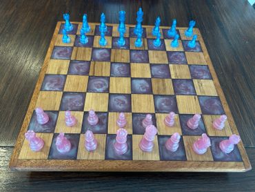 Colorful glass chess pieces on a wooden chessboard.