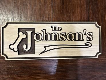 Wooden sign saying "The Johnson's" with a bone design.