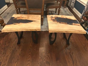 Two wooden stools with dark resin inlays and metal legs.