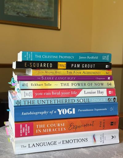 A stack of self-help and spiritual books on a table.