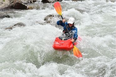 Woman in red kayak going down the river