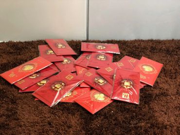 A pile of red envelopes with gold designs on a brown surface.