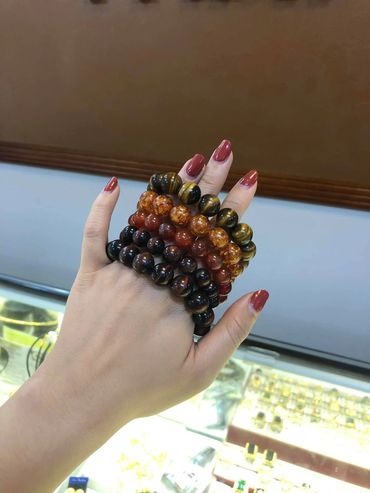 Hand adorned with several beaded bracelets in various earthy tones.